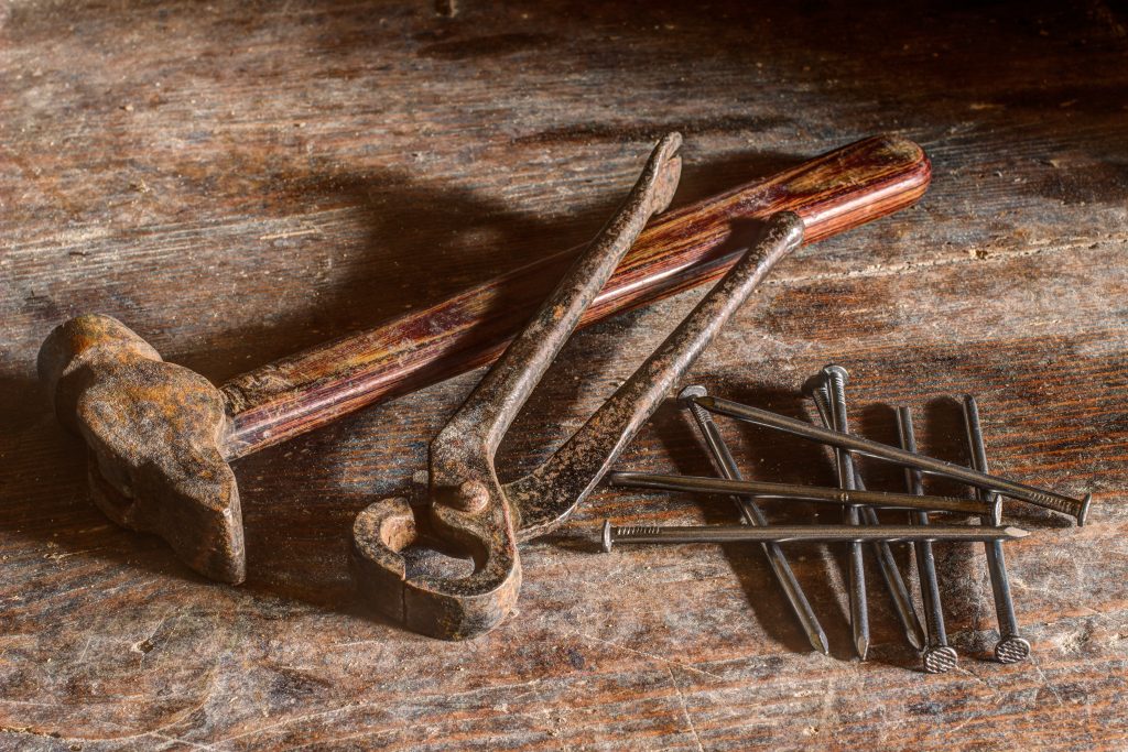 Rostiger Hammer, Zange und Nagel.